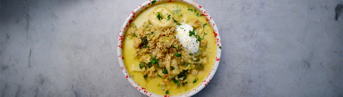 Schüssel mit cremiger Käse-Lauch-Hack-Suppe mit Tortelloni, vegetarischem Hack, Lauchringen und heller Brühe, getoppt mit einem Klecks Sour Cream, frischen Kräutern und grobem Pfeffer – herzhaftes Hauptgericht.