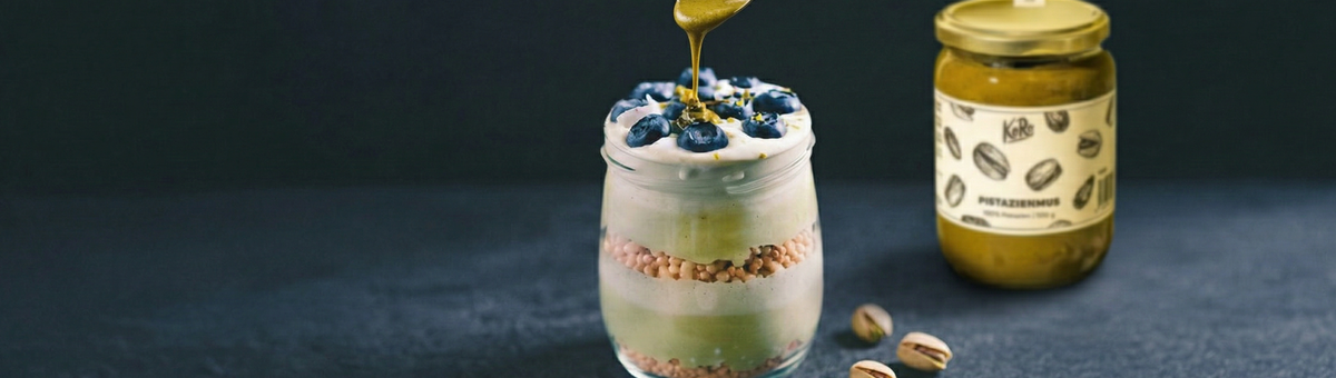 Schichtdessert mit Joghurt, Sojacrispies und Blaubeeren, verfeinert mit KoRo Pistazienmus und Pistazienkernen.