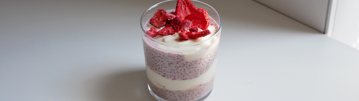 Erdbeer-Chia-Pudding geschichtet mit Joghurt im Glas, garniert mit gefriergetrockneten Erdbeeren.