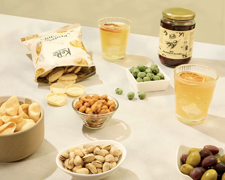 KoRo Aperitivo-Snacks mit Proteinchips, Bio Kalamata Oliven, Pistazien und zwei Drinks mit Orangenscheiben