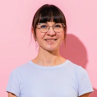 Frau mit Brille und hellem T-Shirt lächelt in die Kamera 