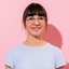 Frau mit Brille und hellem T-Shirt lächelt in die Kamera 