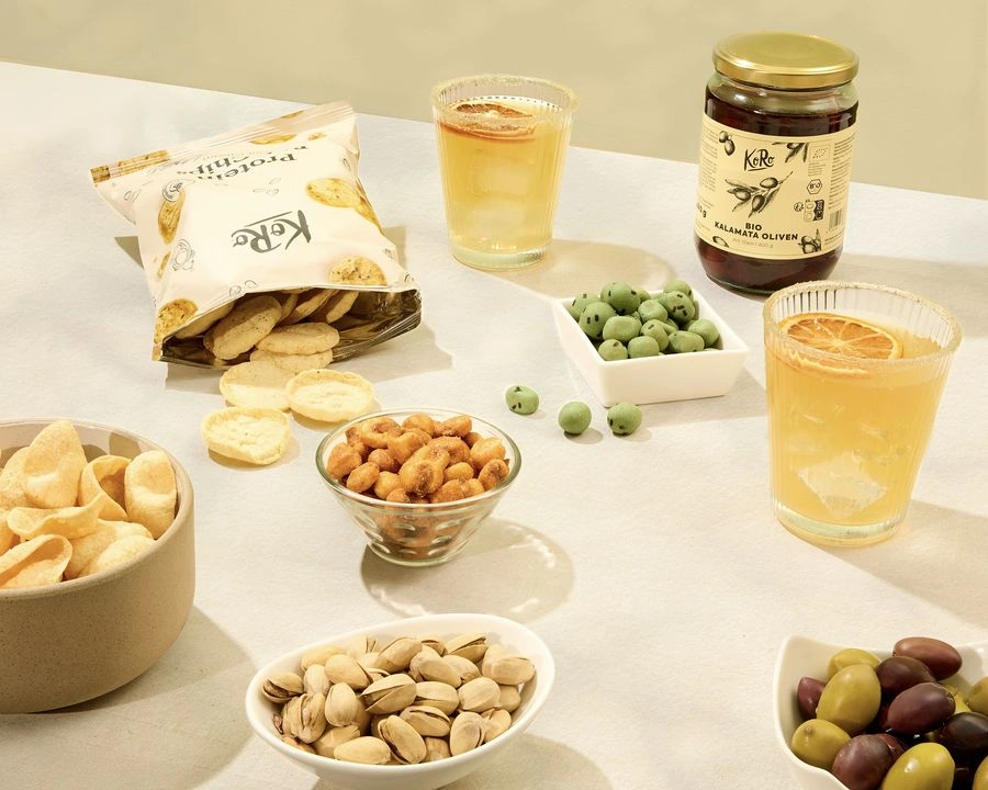 KoRo Aperitivo-Snacks mit Proteinchips, Bio Kalamata Oliven, Pistazien und zwei Drinks mit Orangenscheiben