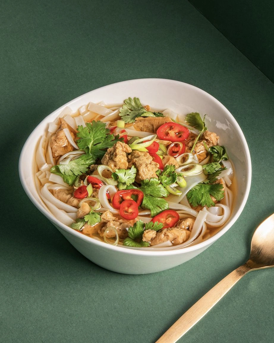 Asiatische Seitan-Nudelsuppe mit Reisnudeln, Frühlingszwiebeln und Chilis in klarer Brühe