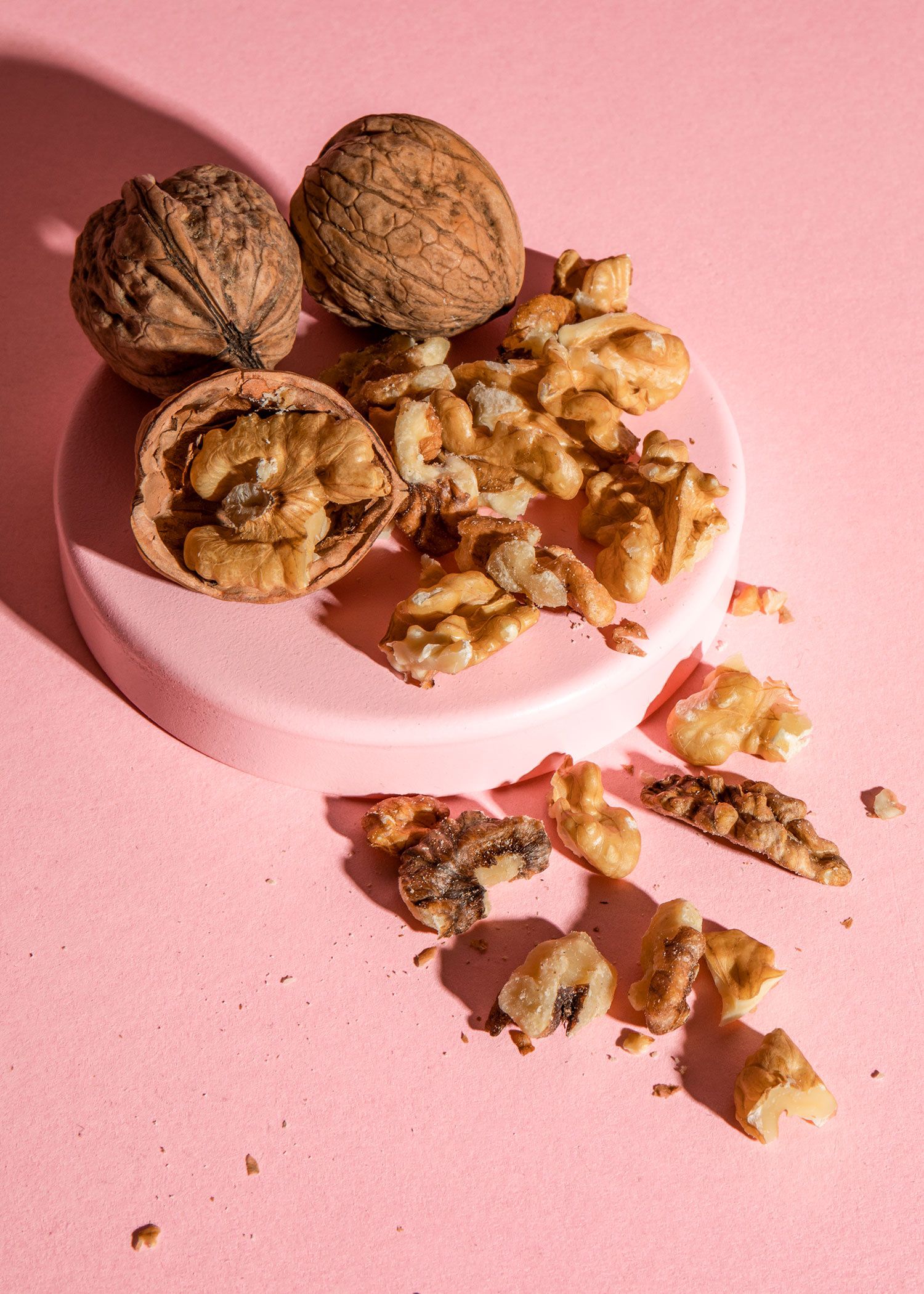 Walnüsse in und ohne Schale auf rosa Untergrund arrangiert
