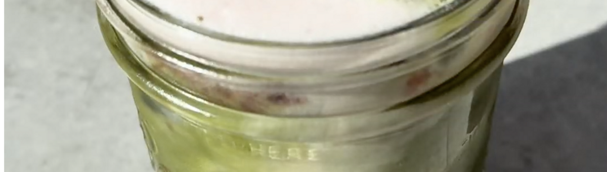 Strawberry Matcha Latte im Glas mit Erdbeerschicht unten, grünem Matcha und Eiswürfeln in der Mitte und rosa Milchschaum oben, mit Glasstrohhalm.