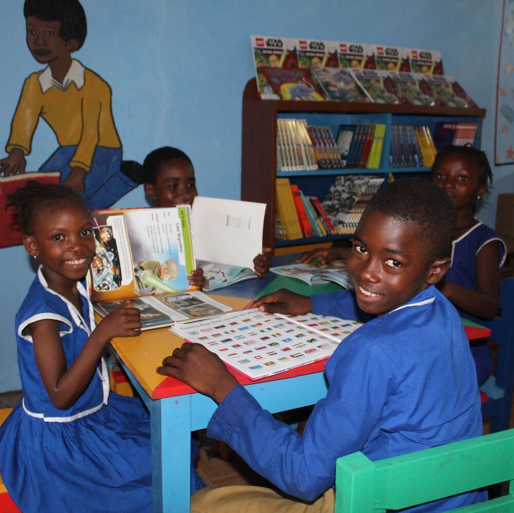 Smilende barn med bøker i Explorer Library United Methodist Church Madonkeh i Sierra Leone