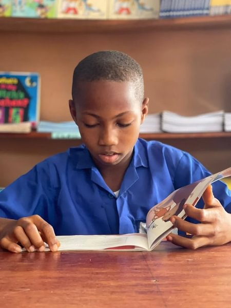 Barn leser book i Explorer Library ved American Calvary Baptist School i Sierra Leone