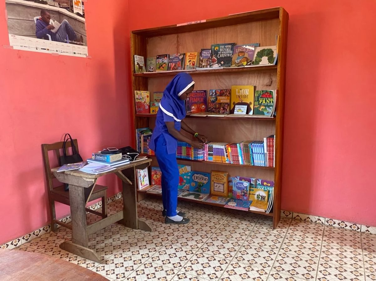 Barn finner bok i bokhylle i Explorer Library ved Namya Islamic Primary School i Sierra Leone