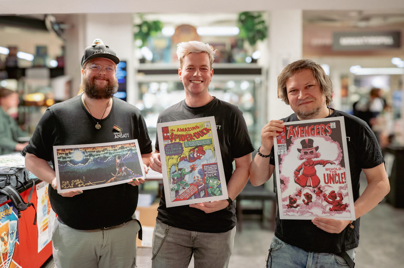 Tre Outland-ansatte med signerte trykk av Don Rosa-forsider