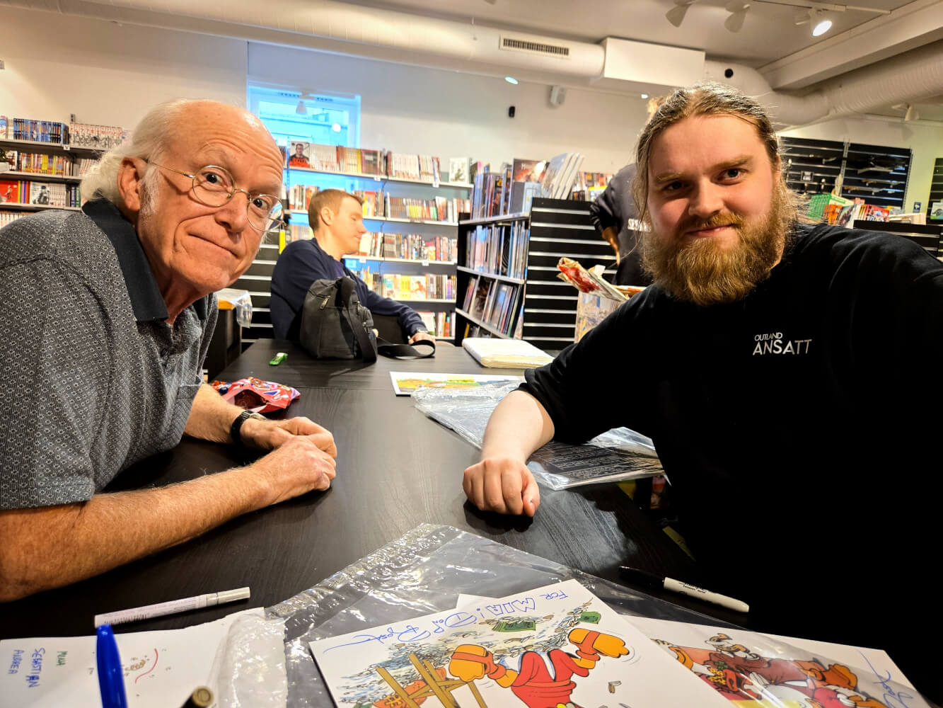 Don Rosa ved signeringsbordet med smilende Outland-ansatt