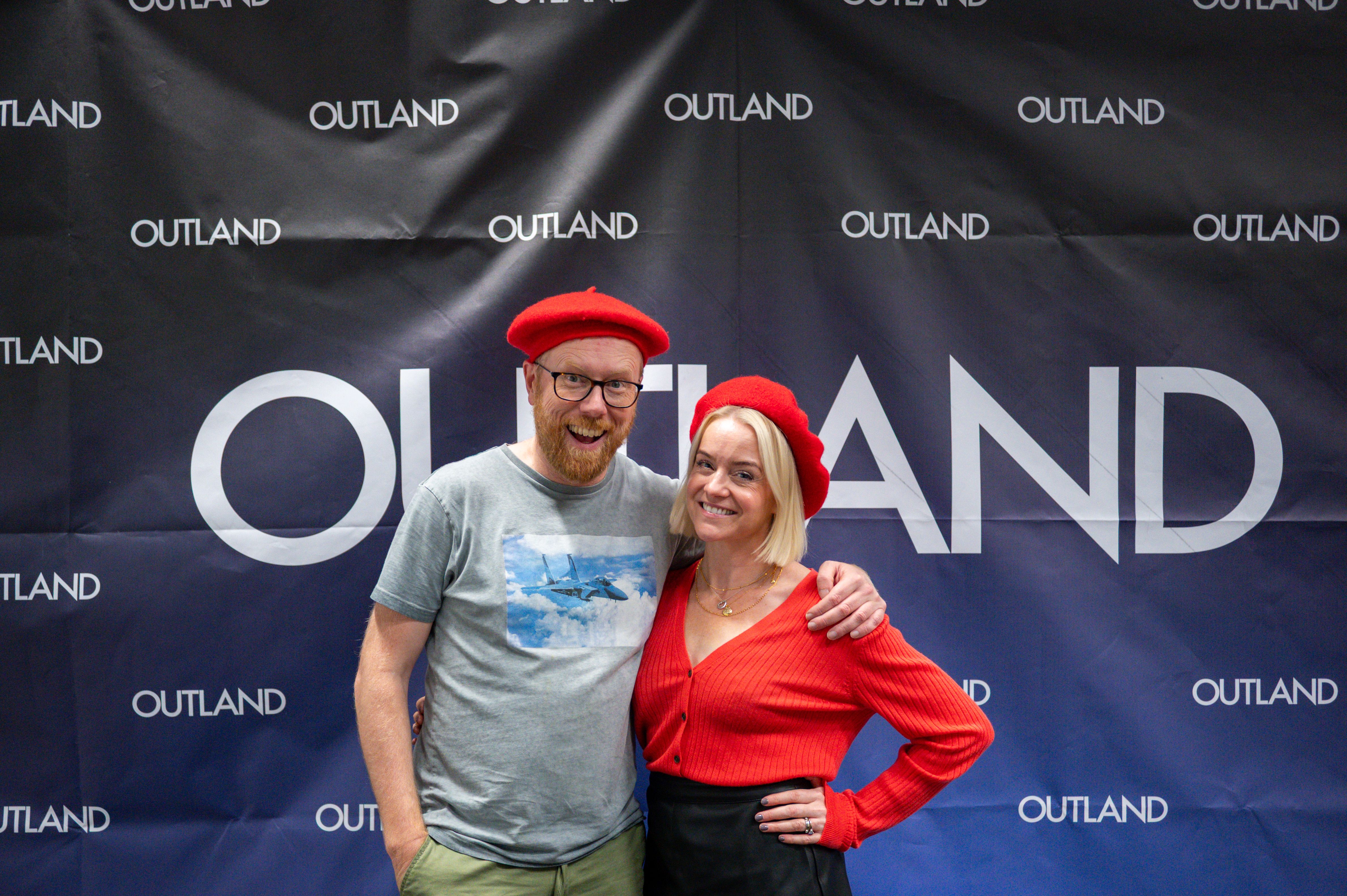 Stemmeskuespillerne Rich Keeble og Billie Fulford-Brown poserer sammen foran Outland-vegg