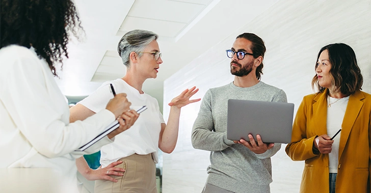 Four colleagues engage in a collaborative discussion in a modern office setting.