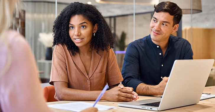 Three individuals in a modern office setting engaged in a professional discussion. 