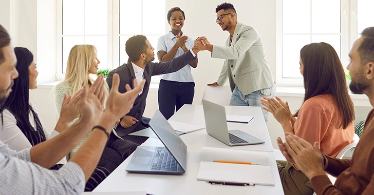 Eight individuals in a bright, modern office setting. 