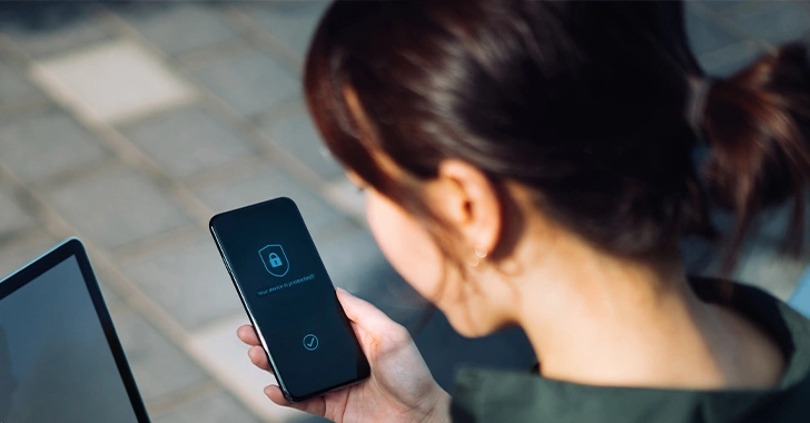 A person is holding a smartphone displaying a lock icon and a security-related interface, suggesting device protection or authentication.