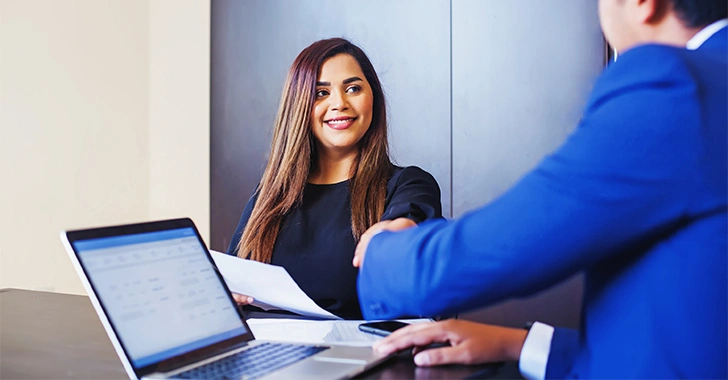 A professional handshake between two individuals in an office setting