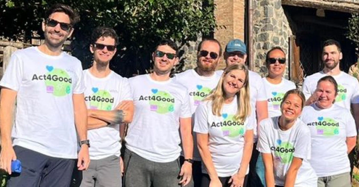 Group of nine people outdoors, wearing matching white t-shirts with 'Act4Good' printed on them, posing together in two rows.