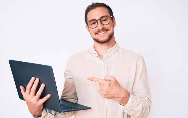 Smiling man with glasses pointing at computer
