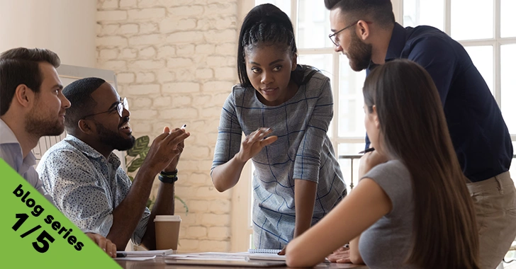 A woman gestures while speaking to a small group of colleagues gathered around a table in a bright office with an exposed brick wall. Overlaid in the bottom left corner is a green banner reading "blog series 1/5."