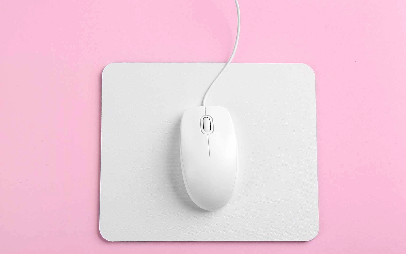 a white mouse on a white mouse mat on a pink background