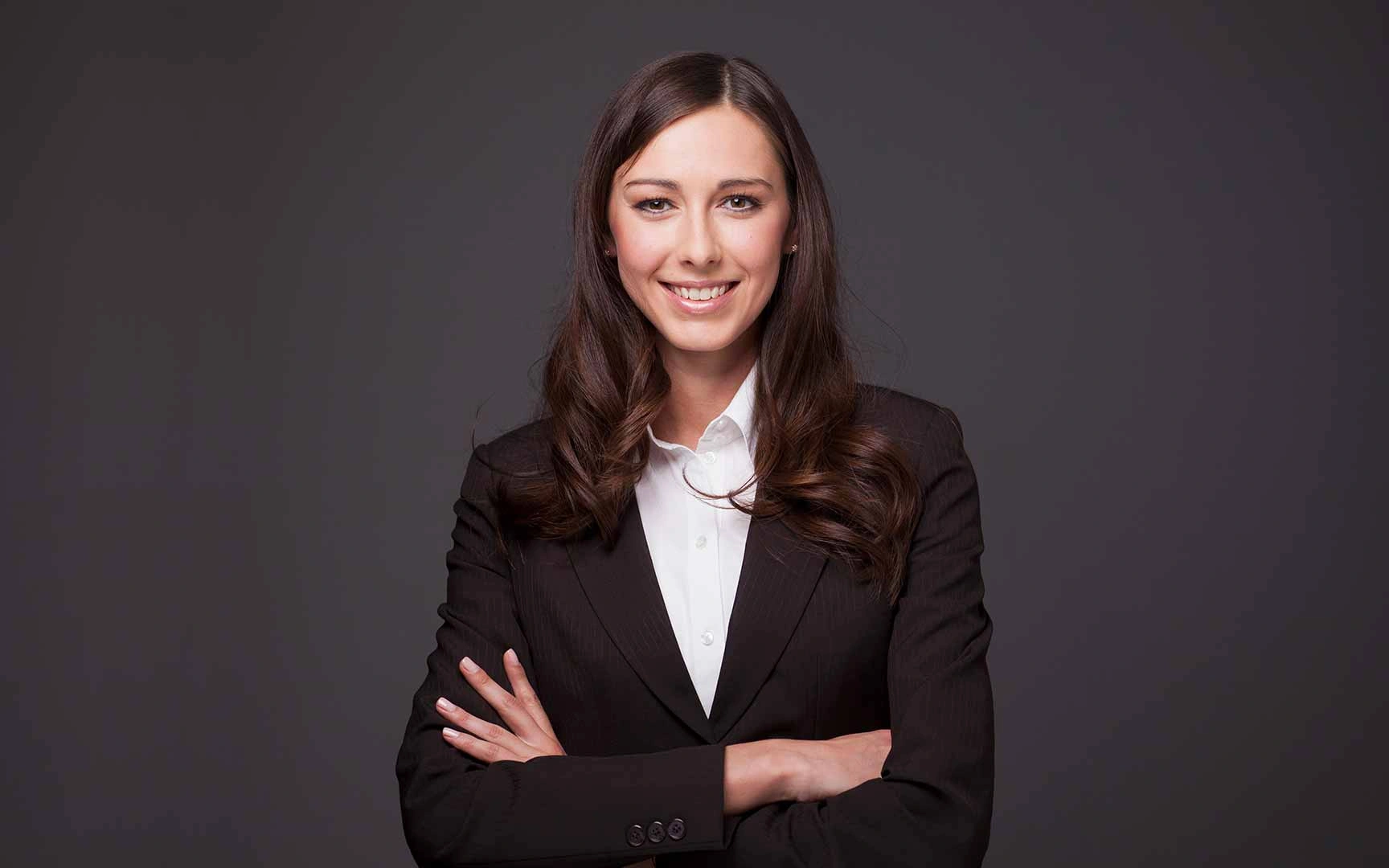 a smartly dressed woman smiling in front of a dark background