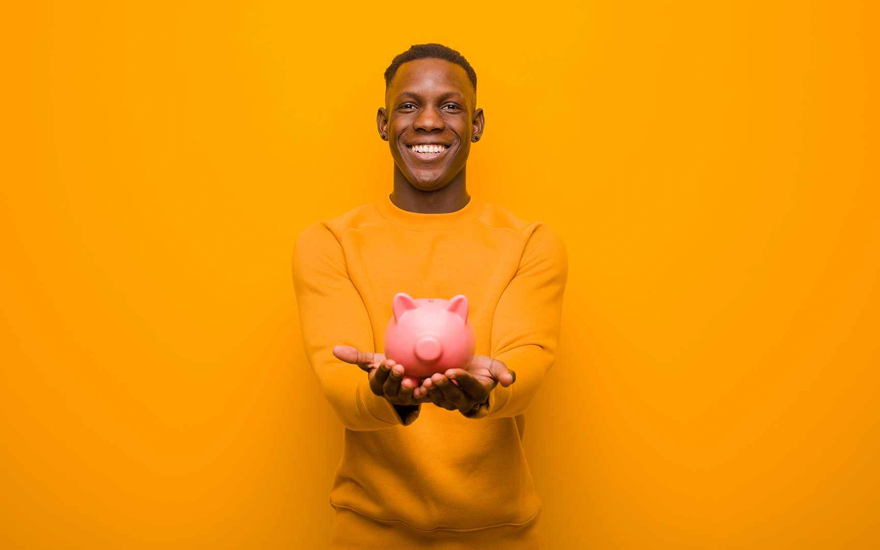 Young man holding a piggy bank