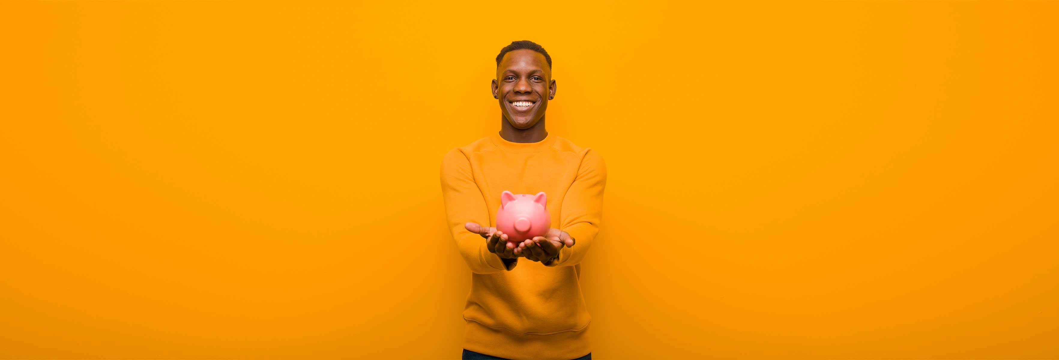 Young man holding a piggy bank