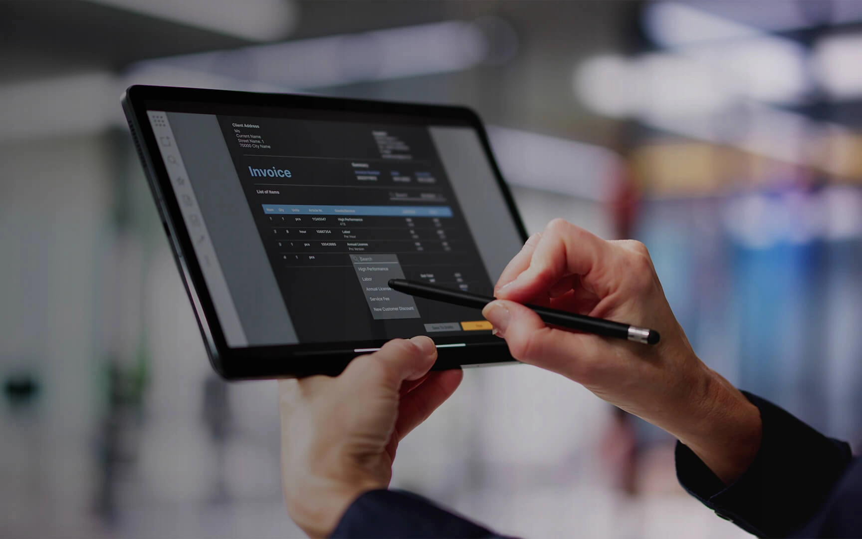 Professional using a tablet to review and edit an invoice in a digital finance application.