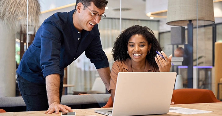 A man and a woman collaborate at a wooden table in a modern office