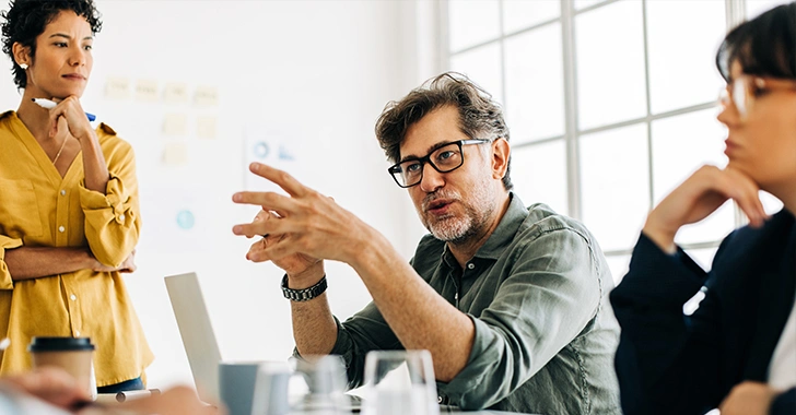 Three professionals in a modern office engage in a collaborative discussion. 
