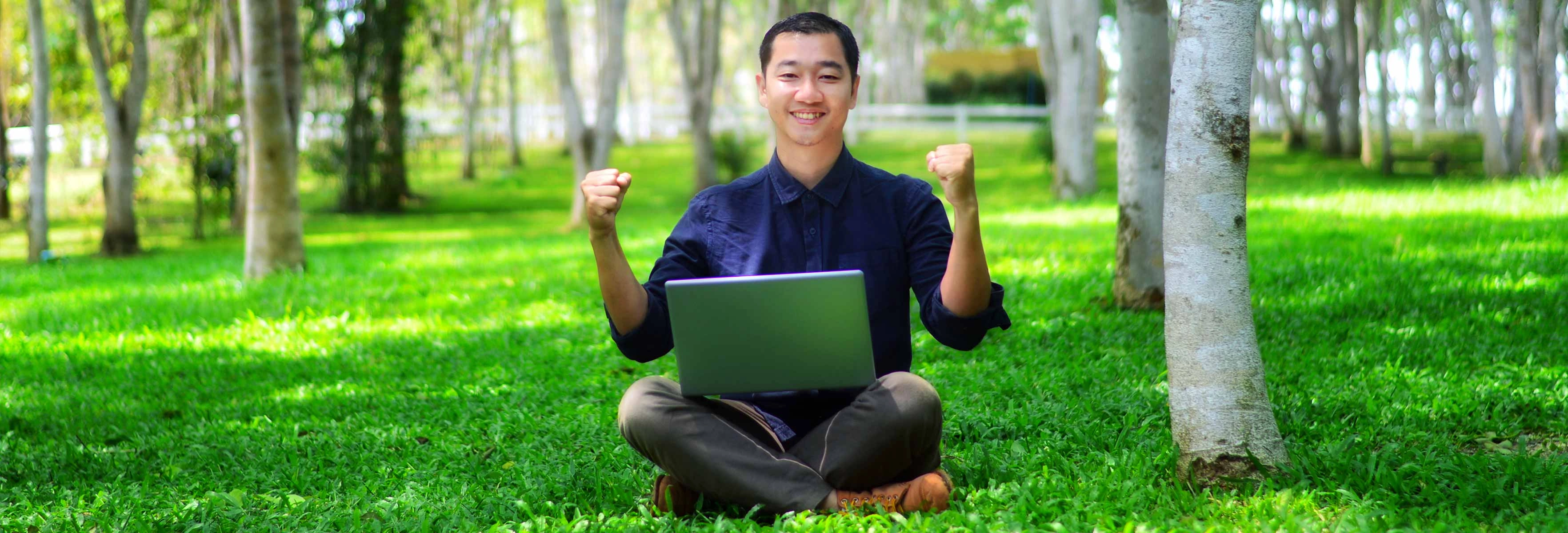 person sitting in forest with laptop