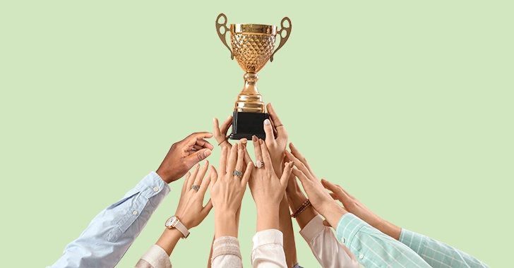 A gold trophy with decorative handles and a black base is centered in the image, surrounded by multiple hands of diverse skin tones and clothing styles reaching upward. 