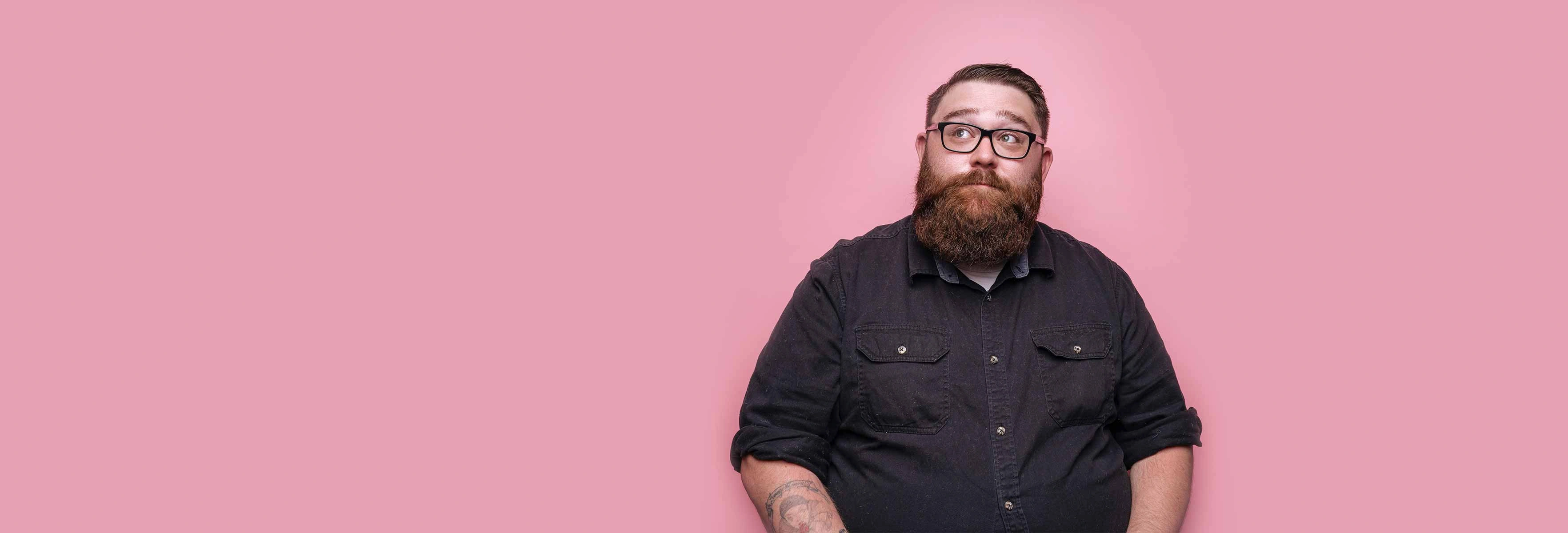a hipster bearded man in a dark shirt and glasses looking happy