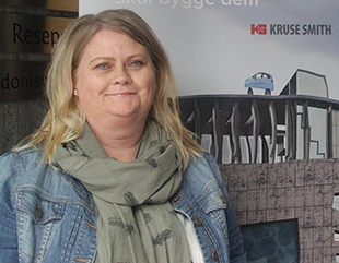 Smilende kvinne foran en Kruse Smith roll up.
