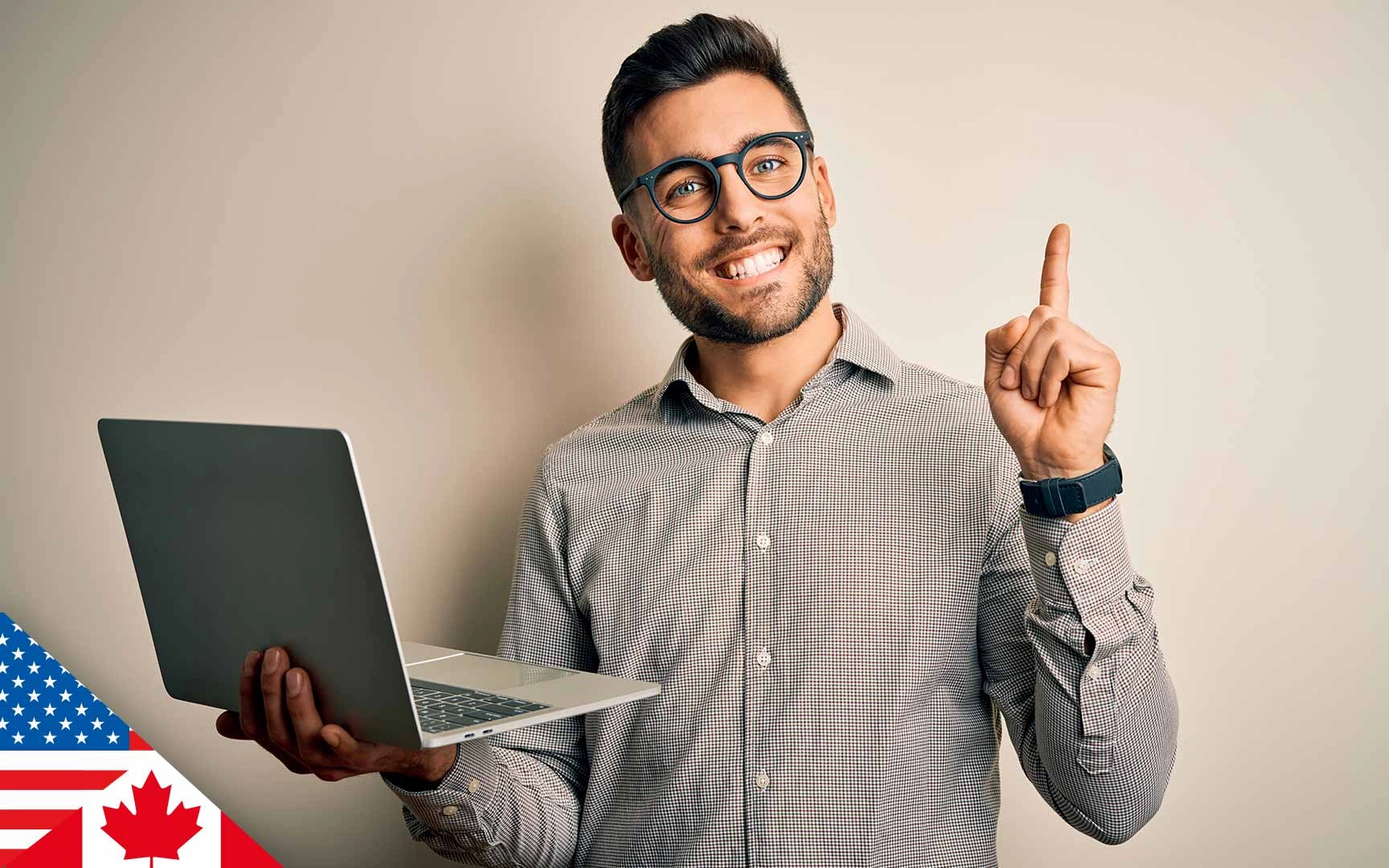 man, smiling and holding laptop; other hand raised, pointing upwards