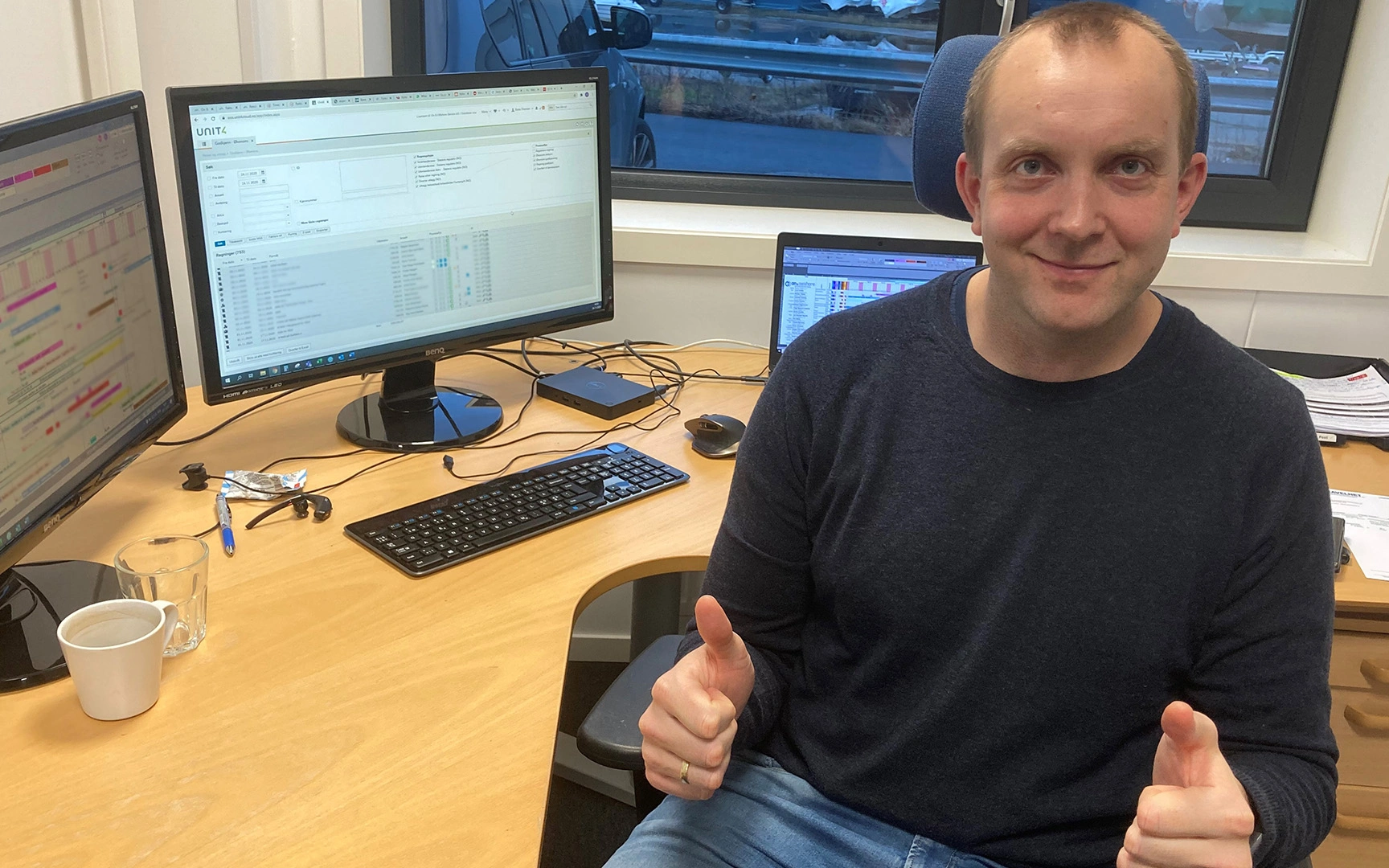 Smilende mann sitter ved pc med tommelen opp