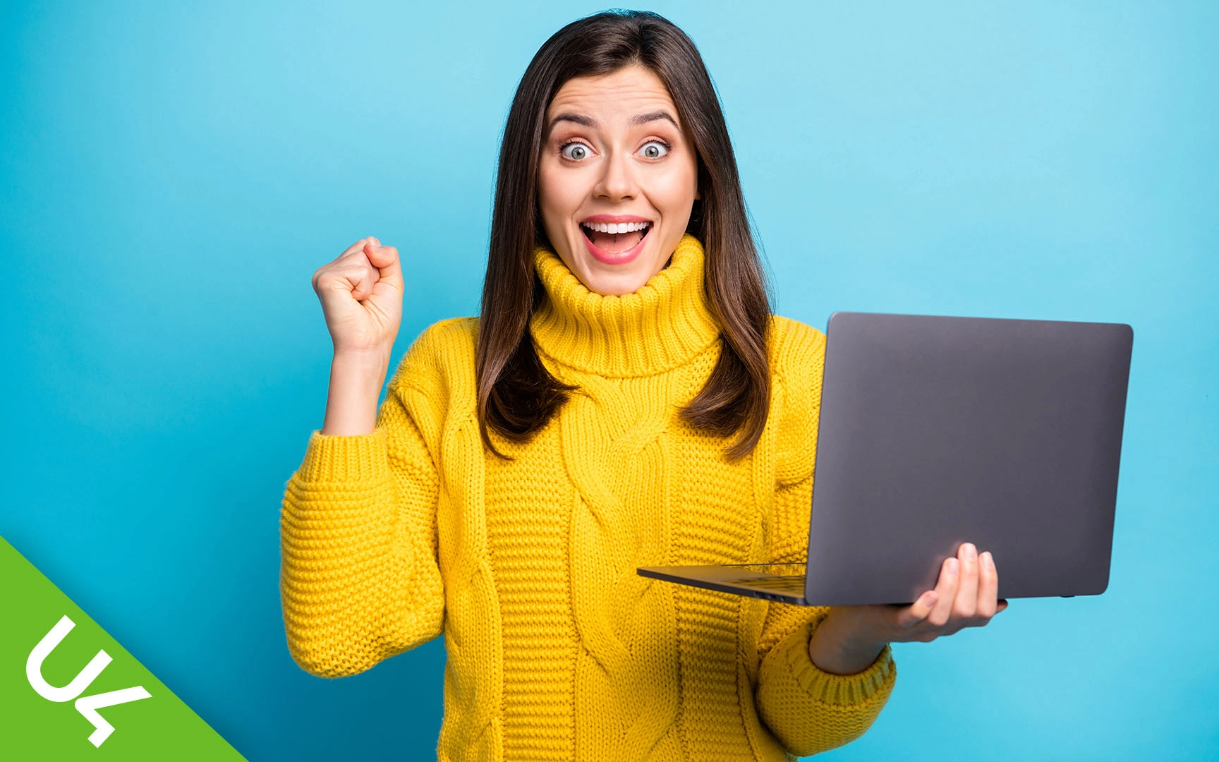 Woman holding laptop in one hand, other hand clenched in celebration