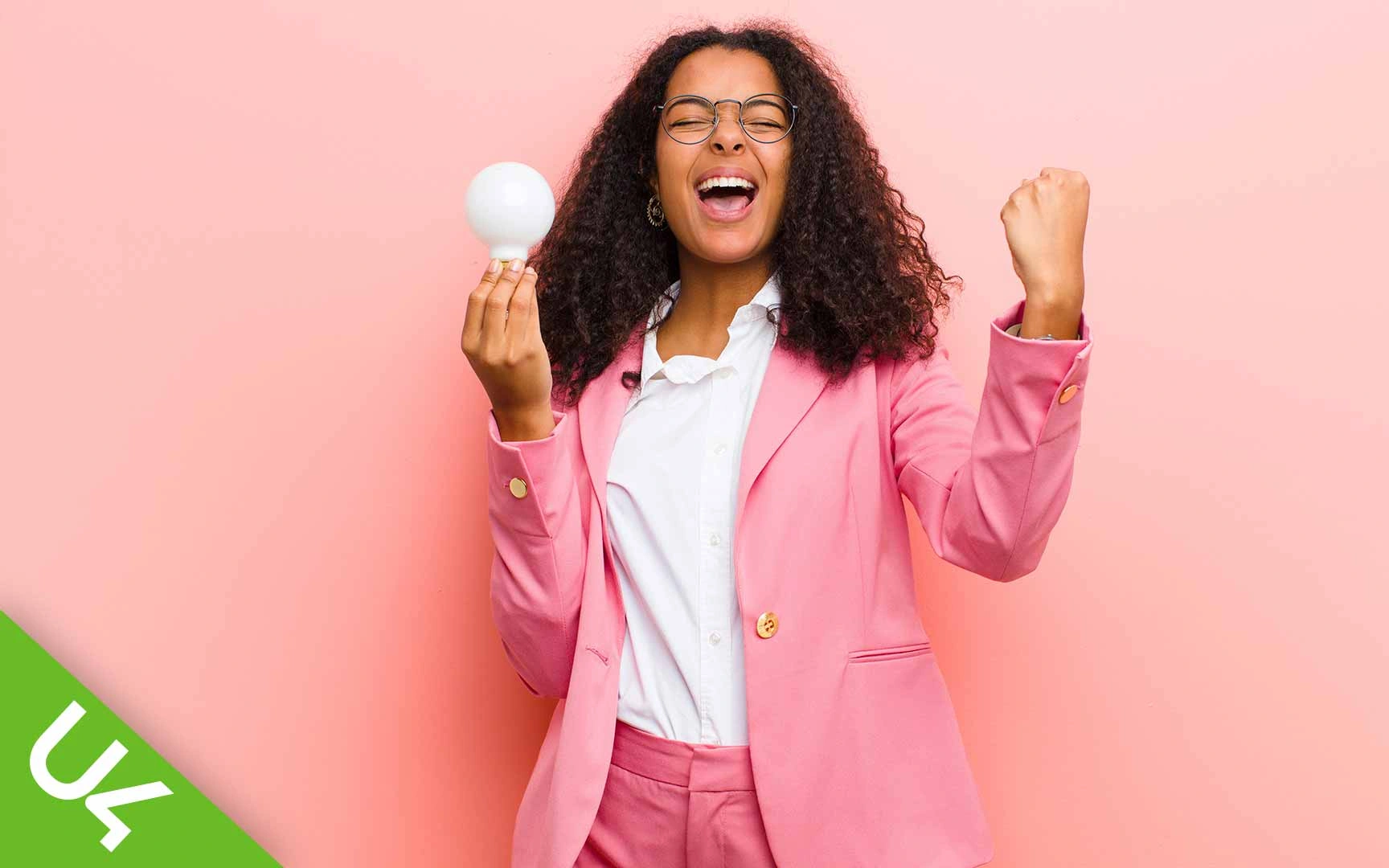 Woman shouting in celebration; holding lightbulb in one hand otehr hand clenched and half raised