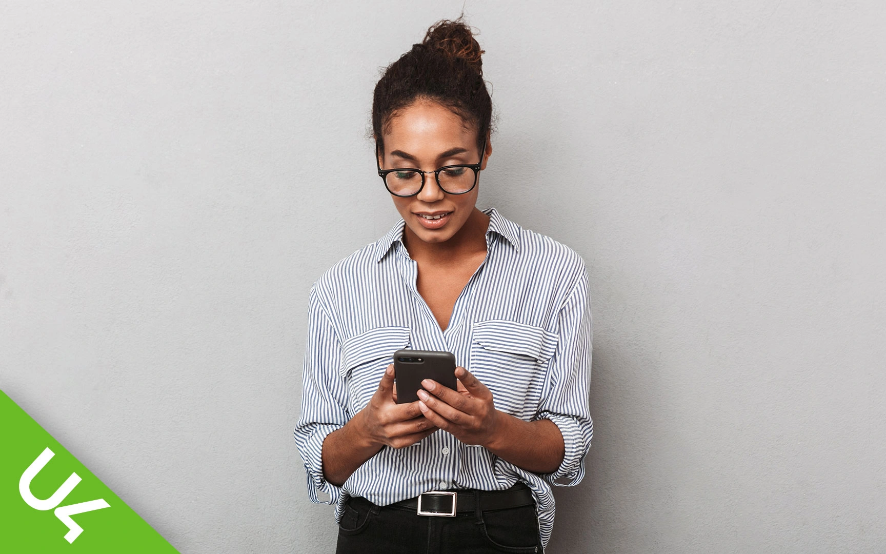 Woman, smiling and looking down at mobile phone, which she is holding in both hands