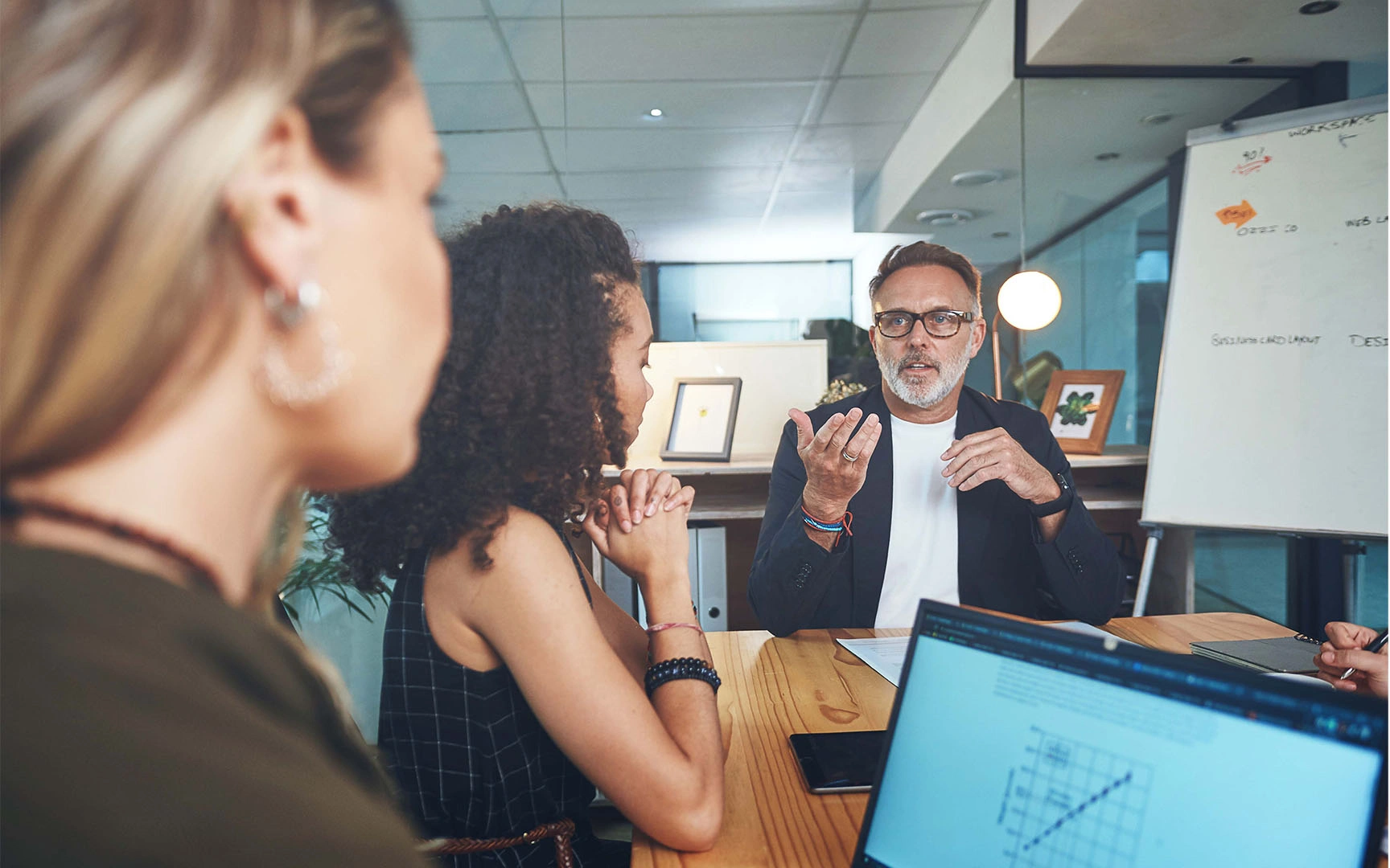 Business professionals collaborating in a modern meeting room, with one participant presenting ideas during a strategic sourcing or procurement discussion while colleagues listen around a conference table.