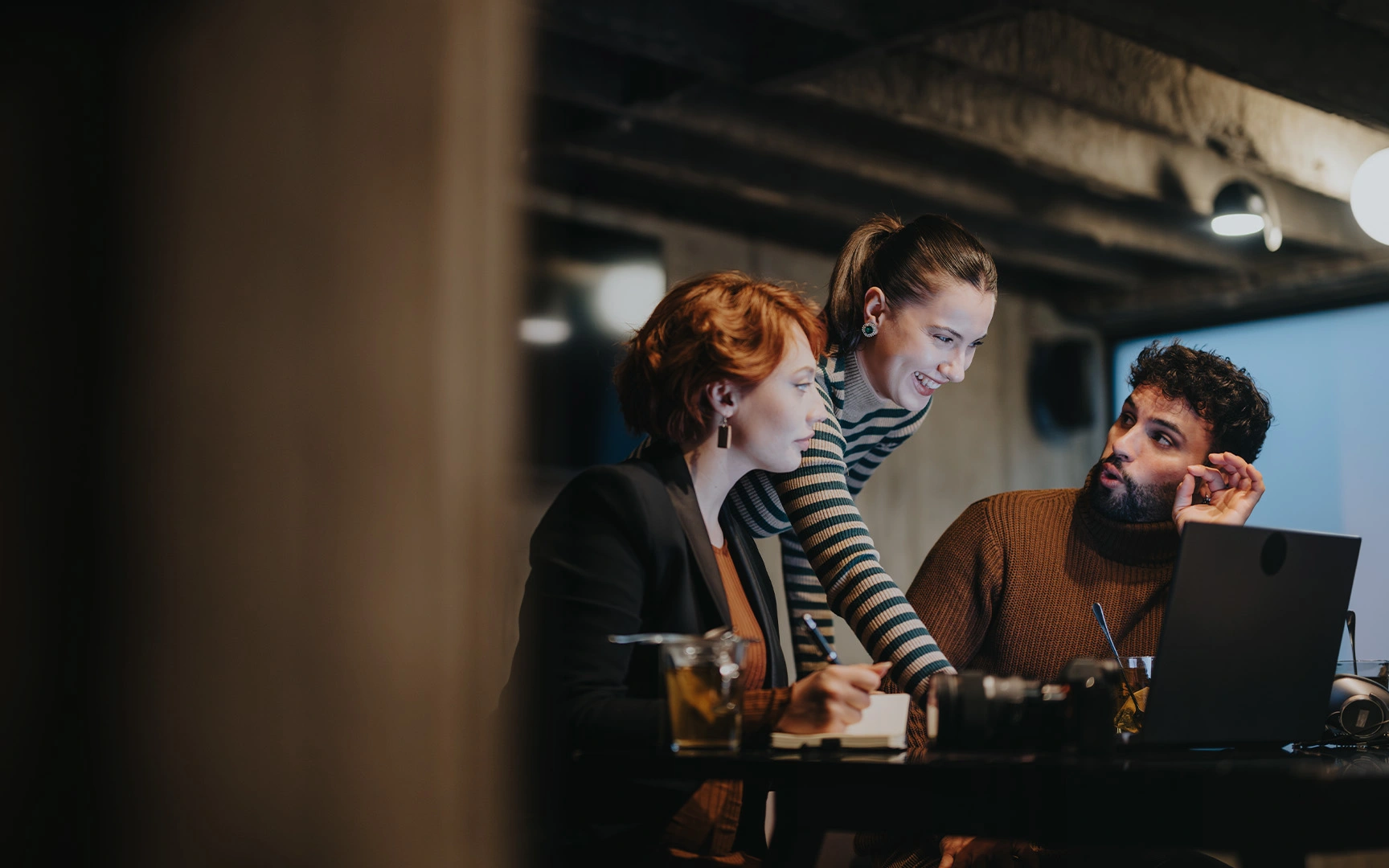 Nonprofit professionals collaborate around a laptop during a team meeting, discussing ideas and workflows that support AI adoption, productivity, and organizational impact.